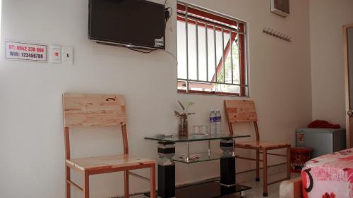 木州县Homstay Sinh thái Cây Sung Mộc Châu的一间设有两把椅子、一张桌子和一台电视的房间