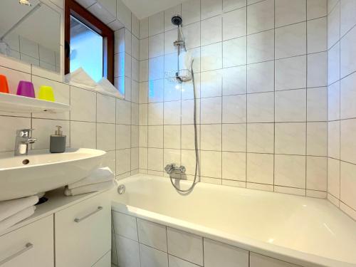 加尔米施-帕滕基兴MittenDrin的白色的浴室设有浴缸和水槽。