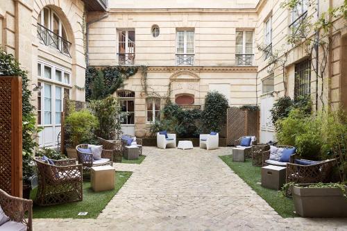 波尔多L'Hôtel Particulier Bordeaux的一座带蓝色枕头和椅子的建筑的庭院