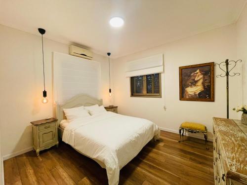 Tirat YehudaOrlinka的卧室配有一张床,墙上挂有绘画作品