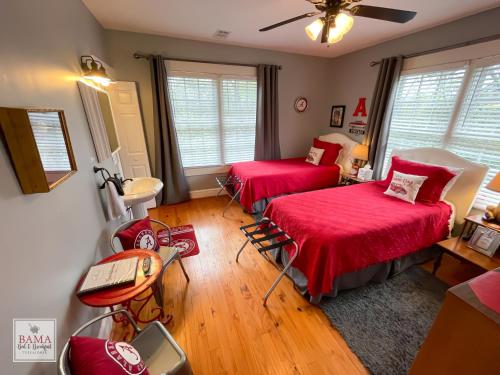 塔斯卡卢萨Bama Bed and Breakfast - Sweet Home Alabama Suite的一间卧室配有两张床、一张桌子和风扇