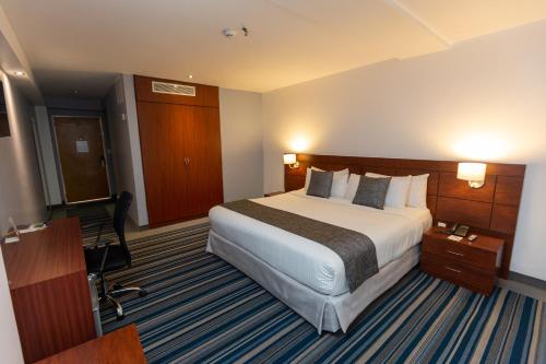 加拉加斯CONTINENTAL ALTAMIRA的酒店客房设有一张大床和一张书桌。