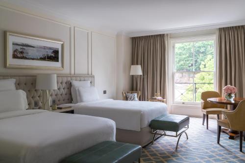悉尼悉尼朗廷酒店的酒店客房设有两张床和一张桌子。