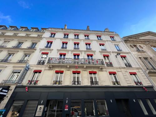 巴黎贝斯特韦斯特爱丽舍王宫酒店的一座白色的大建筑,设有红色的门窗