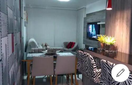 本图贡萨尔维斯Apartamento aconchegante em Bento Gonçalves, próximo ao vale dos vinhedos的客厅配有桌椅和电视。