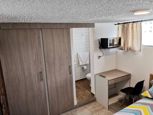 基多Dormitorio Independiente的小房间设有一张床和一张带微波炉的书桌