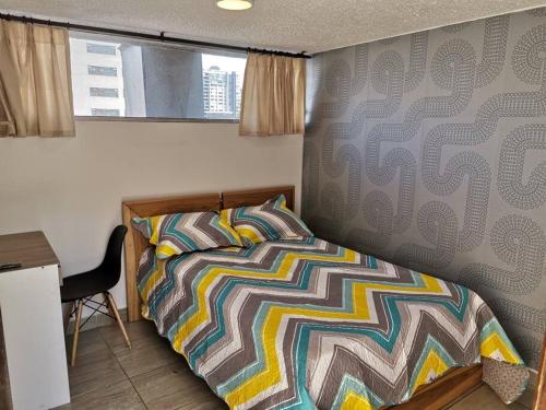 基多Dormitorio Independiente的一间卧室配有一张带五颜六色棉被的床