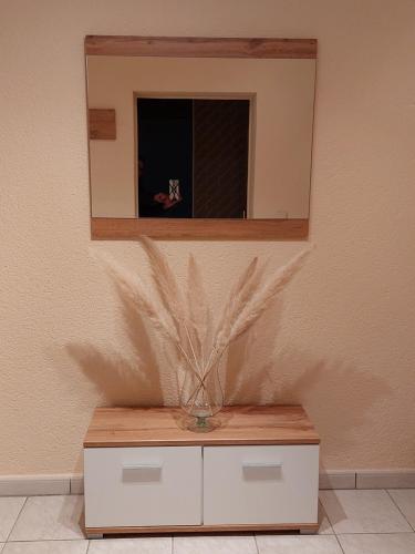 HeddesheimFerienwohnung Juco的壁上镜子,橱柜上有一个花瓶