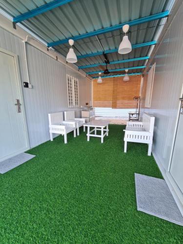 哥打巴鲁Cheqma Tiny Chalet的一个带顶棚的庭院,上面有白色长椅和绿色的草地