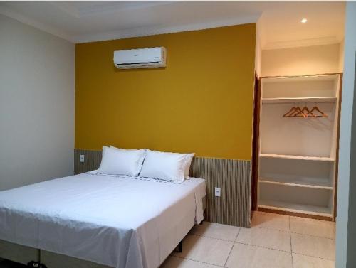 圣米格尔-杜戈斯托苏Pousada Império的卧室配有白色的床和黄色的墙壁