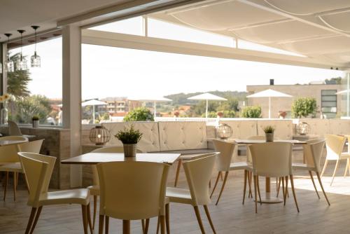 波多诺伏金字塔酒店的餐厅设有白色的桌椅和窗户。