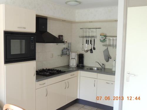 德瓦尔Vinkie的厨房配有白色橱柜和黑微波炉