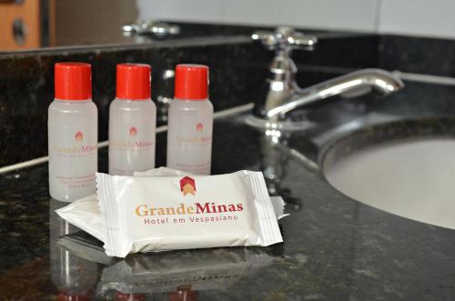 韦斯帕夏诺Hotel Grande Minas的浴室柜台配有3瓶洗发水和盥洗池