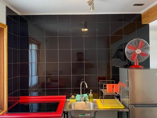 普孔French Andes Apart Hostel的厨房设有水槽和黑色瓷砖墙。
