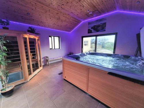 米尔福德Millstone Cottages的大型浴室设有紫色照明的大浴缸
