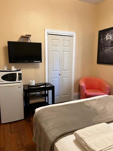 多伦多Adas Guesthouse的酒店客房带一张床、一台电视和一把椅子