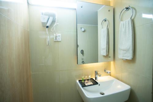 达卡Jatra Hotel Grand Royal的一间带水槽和镜子的浴室以及一部电话
