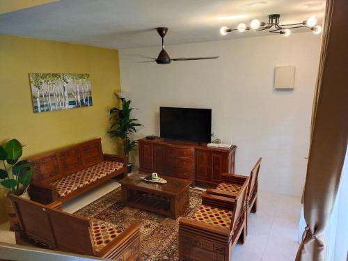 斯里伊斯兰德Kayu Cengal Homestay的客厅配有平面电视和木制家具。