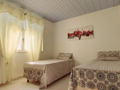 纳塔尔Casa Petit - Banheiro Exclusivo的一间卧室设有两张床和窗户。