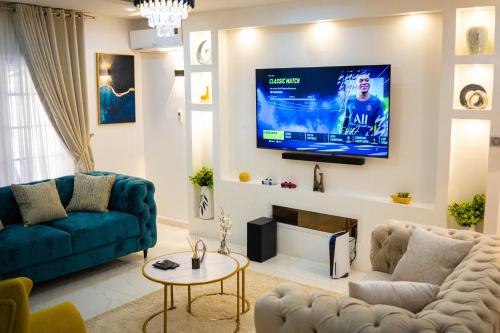阿布贾Morak Homes - Luxury 4 bed home with PS5, 24hrs electricity, Super fast Wifi, Snooker, Games room - in a secured estate的客厅配有沙发和墙上的电视