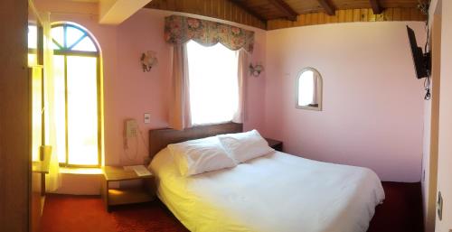 塔尔卡Hotel Cordillera的卧室配有白色的床和2扇窗户。