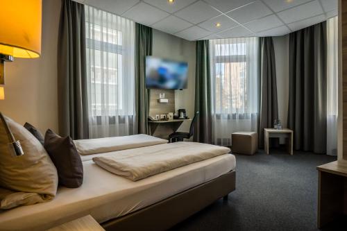 科布伦茨Hotel Hohenstaufen的配有一张床和一张书桌的酒店客房