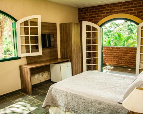 尤西德福拉Pousada Lago das Pedras的一间卧室设有一张床、一台电视和窗户。