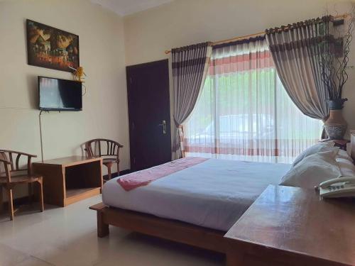 SeturanOmahkoe Syariah Guesthouse RedPartner的一间卧室设有一张床、一台电视和一个窗口。
