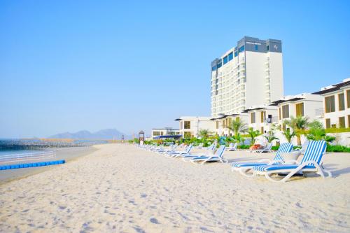 迪巴Mirage Bab Al Bahr Beach Resort的海滩上一排躺椅