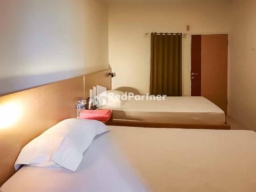 马贾伦卡Wisma Baznas Syariah Majalengka Mitra RedDoorz的酒店客房,设有一张大床和一张大型的四柱床。