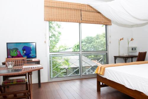 帕拉马里博Boom Apartments的卧室配有一张床、一张书桌和窗户。