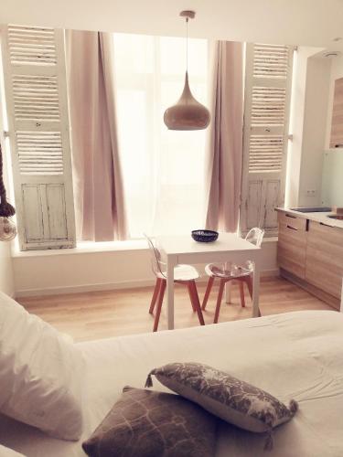 勒克佐Suite 24 Appart'hôtel-3 étoiles的一间卧室配有一张床铺和一张桌子,还设有一间厨房