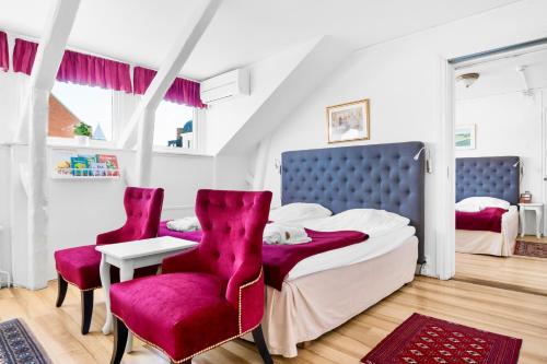 隆德康科迪亚酒店的一间卧室配有一张床和两张红色椅子