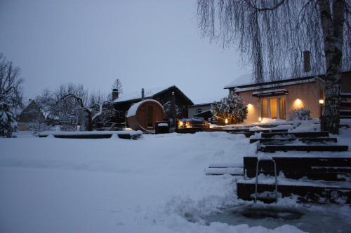 埃尔瓦Purde Puhkemaja - Hot Tub l Sauna l BBQ的雪覆盖的房屋,晚上有灯