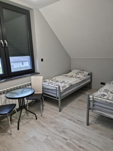 库特诺Noclegi 24/h Leszczynek的一间设有两张床和一张桌子及椅子的房间