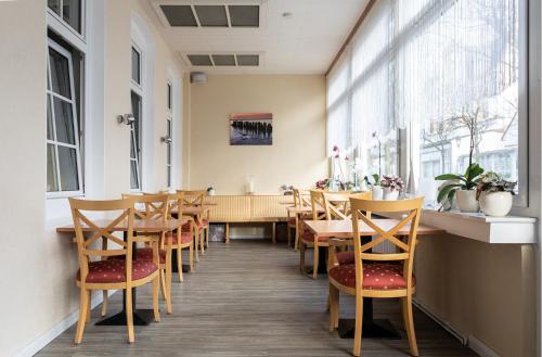 诺德奈Pension Haus Weierts的餐厅设有木桌、椅子和窗户。