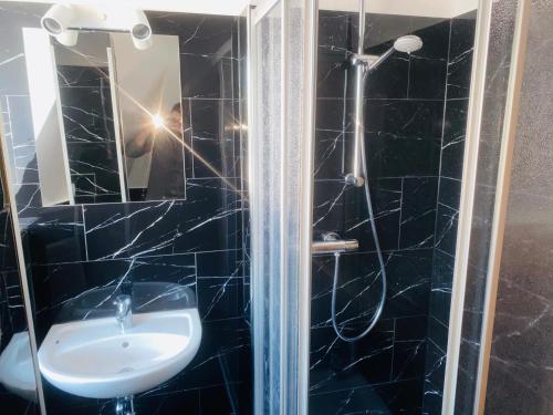 华法林Pic Pension的黑色瓷砖浴室设有水槽和淋浴