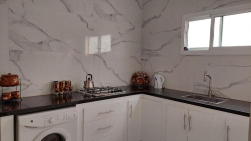 丹吉尔Emplacement idéal的白色的厨房配有水槽和洗衣机