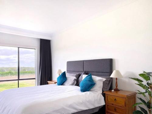 努里乌特帕The Red Door @ Barossa Valley Vineyard View的白色卧室配有一张带蓝色枕头的大床