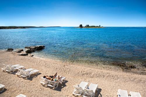 罗维尼Maistra Select Villas Rubin Resort的一群躺在沙滩上的草坪椅子和人