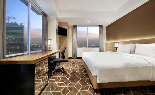 泗水瑞士贝林泗水唐均苏拉巴亚酒店的酒店客房设有一张床、一张书桌和窗户。