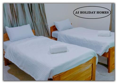CanaguinimJJ Holiday Homes的客房内的两张床和白色床单