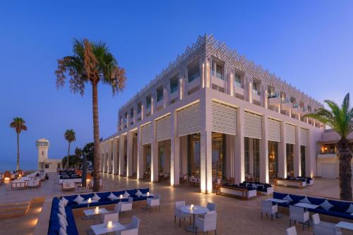 纳祖尔Marchica Lagoon Resort的一座配有桌椅的建筑,棕榈树