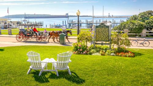 麦基诺岛Island House Hotel的公园,公园里摆放着两把椅子,标志和马车