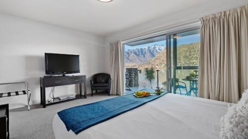 皇后镇Alpine Lakeside Studio的一间卧室设有一张大床和一个大窗户
