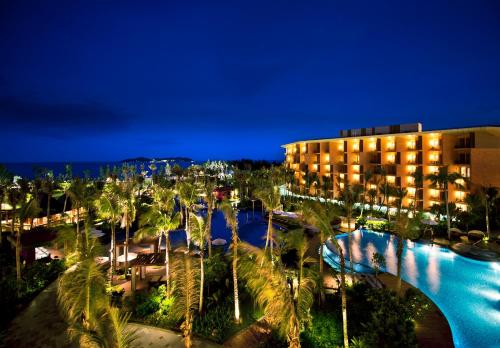 三亚三亚海棠湾万达嘉华度假酒店的夜间有游泳池和棕榈树的酒店