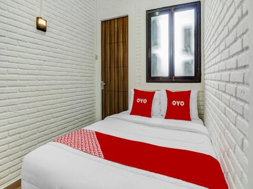 巴图Super OYO 90828 Ara Guest House的一张红色和白色的床,上面有两个红色的枕头