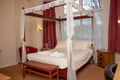 利兹阿斯科特格兰奇酒店 - 沃均餐厅的一间卧室配有一张天蓬床和一张桌子