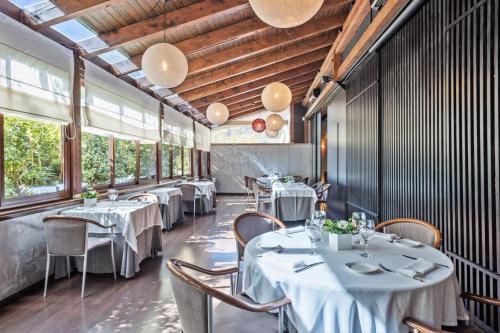 安道尔城阿克塔艺术酒店的餐厅设有白色的桌椅和窗户。
