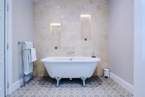 切斯特Cromwell House的浴室铺有瓷砖地板,配有白色浴缸。